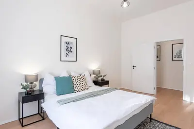 a bedroom with a large white bed and two tables at Unique Old Town 2BR Oasis with Sofa Bed in Prague