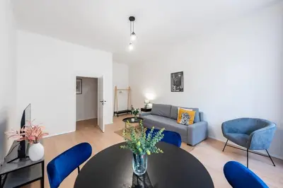 a living room with a table and blue chairs at Urban 2BR Haven with Sofa Bed in Central Prague in Prague