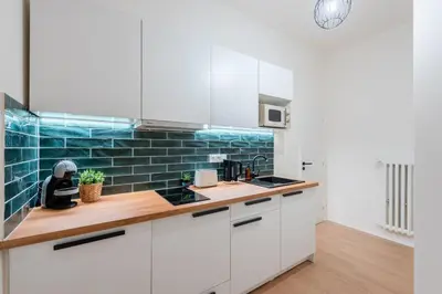 a kitchen with white cabinets and blue subway tiles at Urban 2BR Haven with Sofa Bed in Central Prague in Prague
