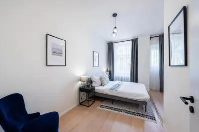 a white bedroom with a bed and a chair at Urban 2BR Haven with Sofa Bed in Central Prague in Prague