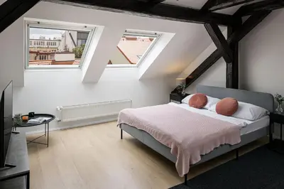 a bedroom with a bed and two windows at Under the Beams - Designer Prague Old Town Loft in Prague
