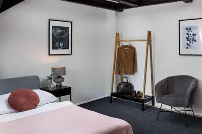 a bedroom with a bed and a chair at Under the Beams - Designer Prague Old Town Loft in Prague