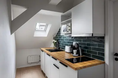 a kitchen with white cabinets and green tile on the wall at Zesty Family Friendly Elevator Access Old Town in Prague