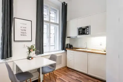 a kitchen with white cabinets and a white table and chairs at Friendly Studio for Two Old Town in Prague