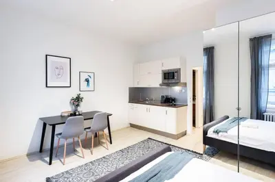 a white apartment with a dining table and a bedroom at Welcoming Studio in Historic Prague in Prague