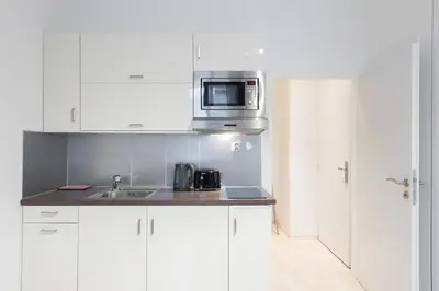 a white kitchen with a sink and a microwave at Welcoming Studio in Historic Prague in Prague