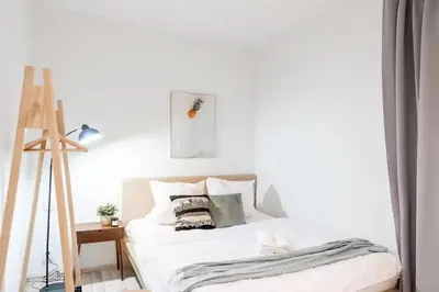 a white bedroom with a bed and a ladder at Peaceful Chic Studio in Central Prague in Prague