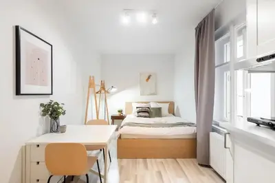 a white bedroom with a bed and a table at Peaceful Chic Studio in Central Prague in Prague
