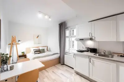 a kitchen with white cabinets and a bed in the background at Peaceful Chic Studio in Central Prague in Prague
