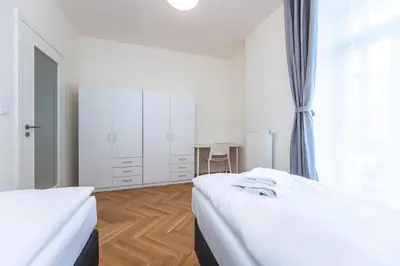 a white bedroom with two beds and a window at Apartments Seifertova in Prague