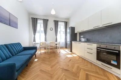a living room with a blue couch and a kitchen at Apartments Seifertova in Prague