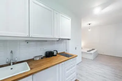 a kitchen with white cabinets and a wooden counter top at Tranquil Prague Studio Gem in Prague