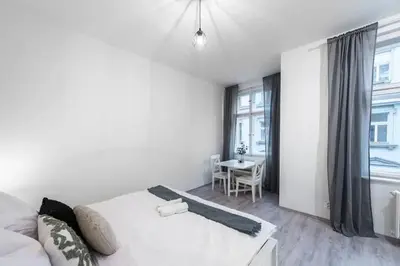 a white bedroom with a bed and a table at Tranquil Prague Studio Gem in Prague