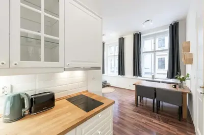 a kitchen with white cabinets and a table and a sink at Metropolitan Prague Apt with Amenities in Prague