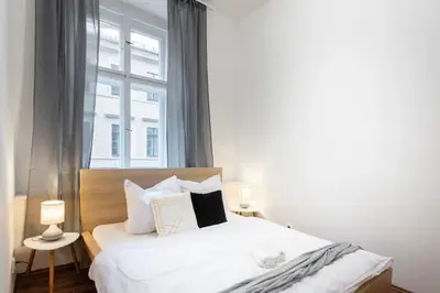 a bedroom with a bed with white sheets and a window at Metropolitan Prague Apt with Amenities in Prague