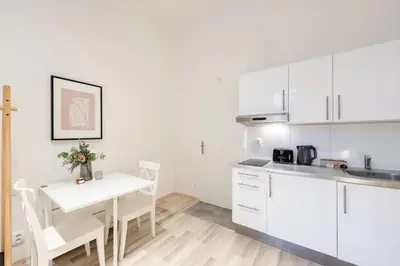 a kitchen with white cabinets and a white table and chairs at Romantic Old Town Studio in Prague