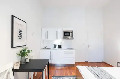 a kitchen with white cabinets and a black table at Sunny Old Town Studio in Prague