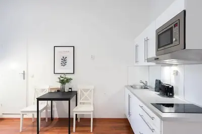 a white kitchen with a black table and chairs at Sunny Old Town Studio in Prague