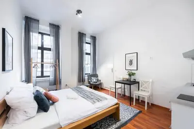 a white bedroom with a bed and a desk at Sunny Old Town Studio in Prague