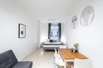 a white living room with a bed and a table at Vast Central Old Town Studio For 3 in Prague