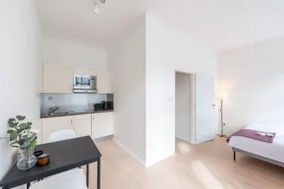 a white room with a dining table and a kitchen at Vibrant Old Town Studio in Prague