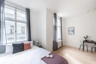 a white bedroom with a large window and a bed at Vibrant Old Town Studio in Prague