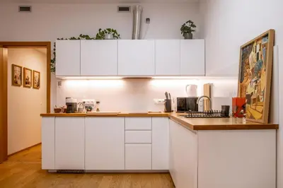a kitchen with white cabinets and a wooden floor at New studio, King bed, Free parking, Terrace in Prague