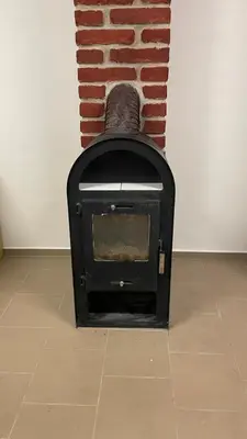a black stove sitting in front of a brick fireplace at Domek na statku in Klipec