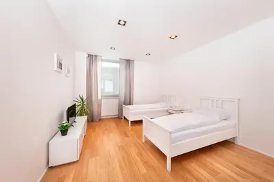 a white living room with white furniture and wood floors at Hotel & Hostel Letov in Prague