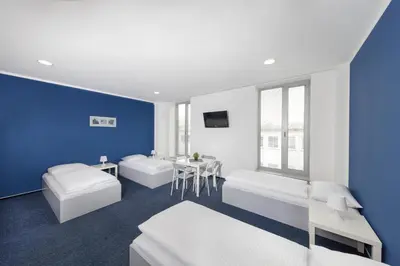 a blue and white room with two beds and a table at Hotel & Hostel Letov in Prague