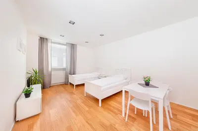 a white living room with a table and a couch at Hotel & Hostel Letov in Prague