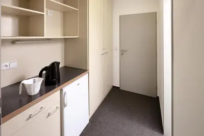 a kitchen with white cabinets and a black counter top at Hotel & Hostel Letov in Prague