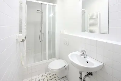 a white bathroom with a toilet and a sink at Hotel & Hostel Letov in Prague