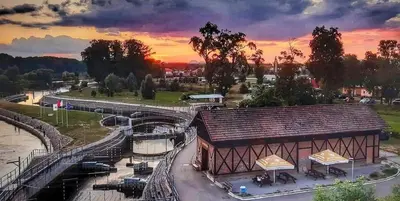 a building next to a river with a sunset in the background at Centrální chata Kanoistika Roudnice in Vědomice