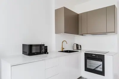 a white kitchen with a microwave and a stove at Blueground Rostovska str nr park foodie area PRG-28 in Prague