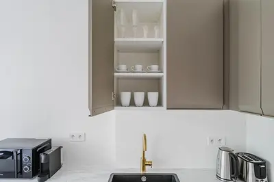 a kitchen with a sink and a cupboard with cups at Blueground Rostovska str nr park foodie area PRG-28 in Prague