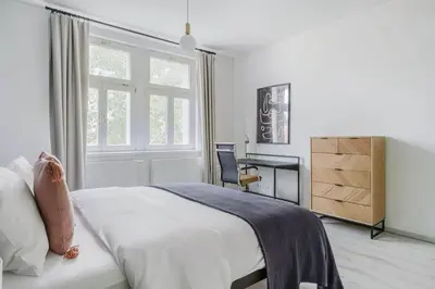 a white bedroom with a bed and a desk at Blueground Rostovska str nr park foodie area PRG-28 in Prague