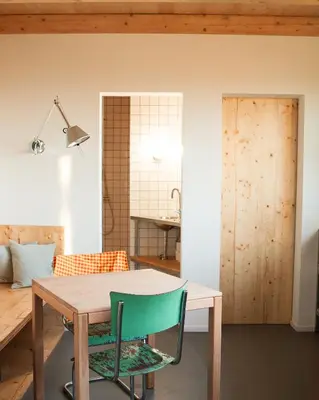 a dining room with a table and a green chair at Veritas Beyond Glamping in Hošťka