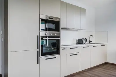 a white kitchen with white cabinets and appliances at Blueground Prague 3 new build balcony PRG-37 in Prague