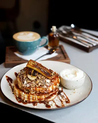 a plate of pancakes and a cup of coffee on a table at Apartment Dusni in Prague