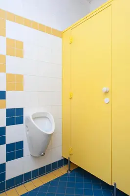 a bathroom with a urinal and a yellow door at Roosevelt Hostel in Prague