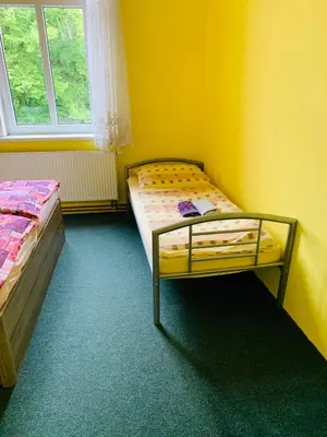 a bedroom with two beds in a yellow room at Penzion Eška s Pivovarem MJ in Jince