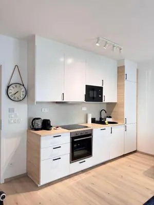 a kitchen with white cabinets and a clock on the wall at Stylish Modern Studio, Large Balcony, Prague 3 in Prague