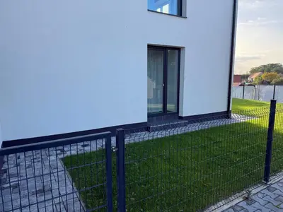 a fence next to a white building with a window at Byt apartman 72m2 private garden PARKING FREE in Prague
