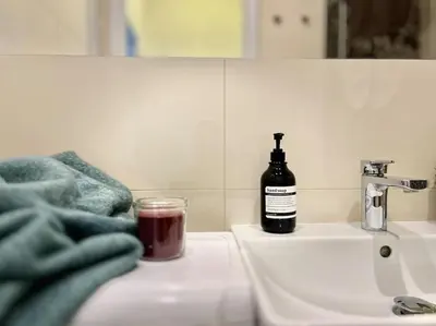 a bottle of soap sitting on a bathroom sink at Sunlit - Prague Apartment in Prague
