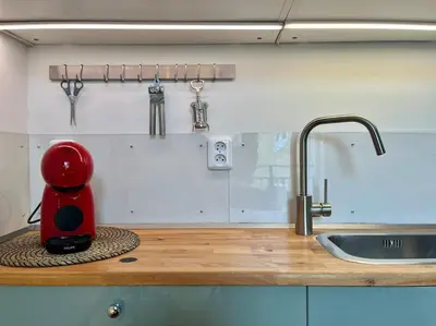a red coffee maker sitting on a counter next to a sink at Sunlit - Prague Apartment in Prague