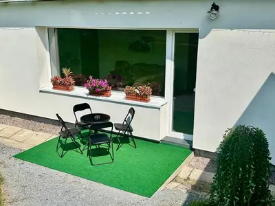 a patio with a table and chairs on a green rug at Dolpo 55 in Benešov