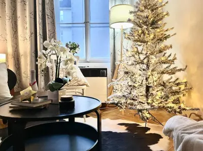 a table with a vase of flowers on it with a christmas tree at Wenceslas - Prague Apartment in Prague