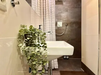 a bathroom with a white sink and a plant at Pine - Prague Apartment in Prague