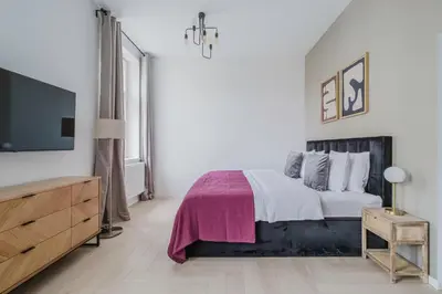 a white bedroom with a bed and a flat screen tv at Blueground Žižkov nr University of Economics PRG-36 in Prague